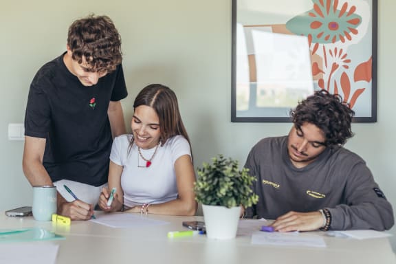two men and a woman at a desk collaborating on paperwork