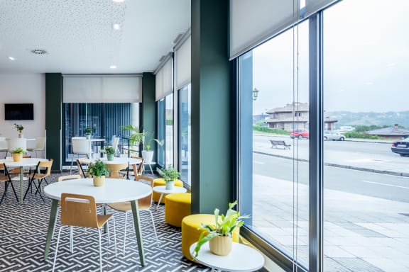 a lounge area with tables and chairs and large windows