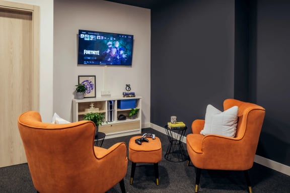 a living room with two orange chairs and a television