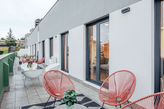 a patio with red chairs and tables and a white building