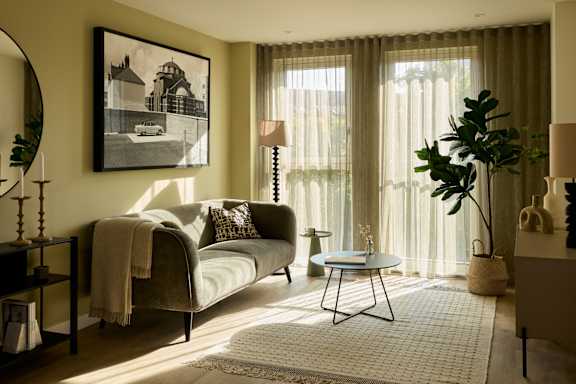 A living room with a grey couch and a framed picture on the wall.