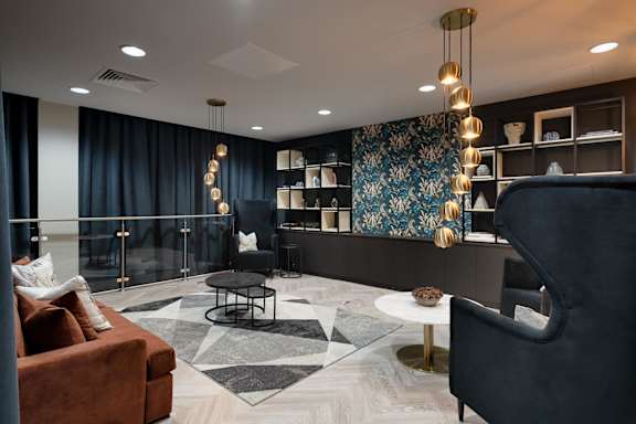 a lobby with couches and chairs and a wall with a tapestry