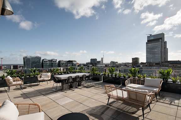 a roof terrace with tables and chairs and a view of the city