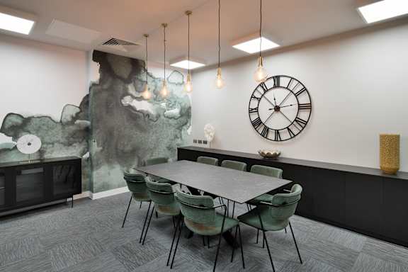 a dining room with a table and chairs and a clock on the wall