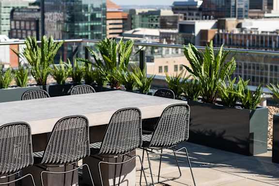 a large table and chairs on a balcony with a view of the city
