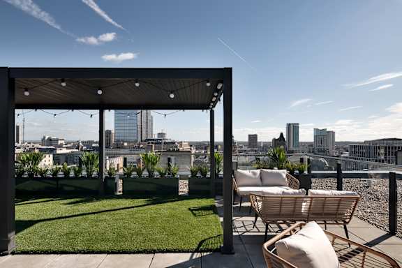 a view of the city from a roof top terrace with chairs and grass