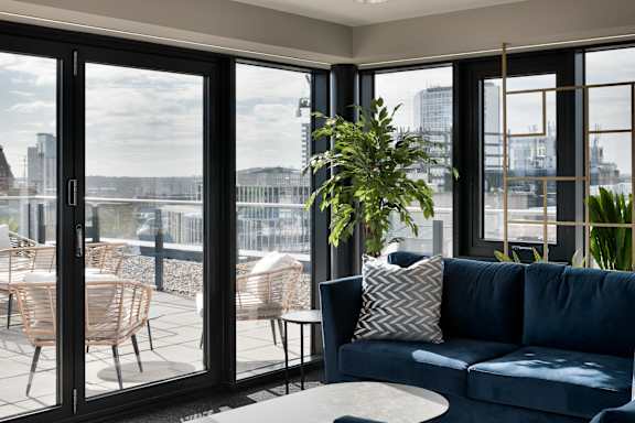 a living room with a blue couch and a balcony with a city view