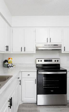 a kitchen with white cabinets and black and white appliances