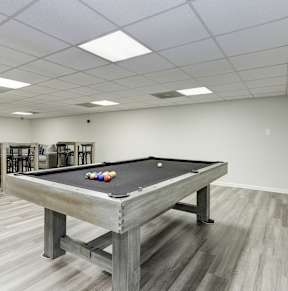 A room with a pool table and bar stools.