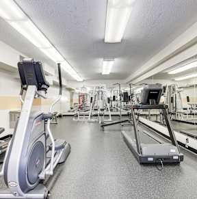 a gym with cardio equipment and weights on the floor