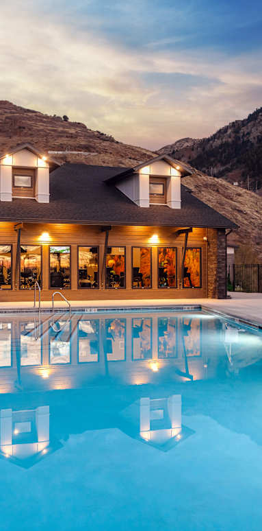 A large house with a pool in the foreground and mountains in the background.