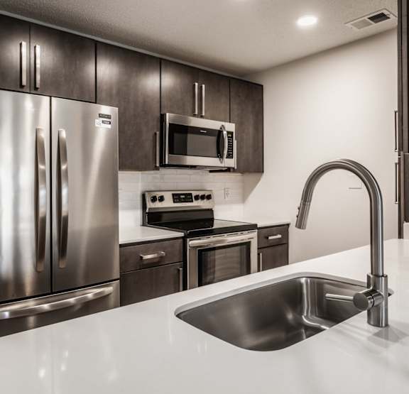 a kitchen with stainless steel appliances and a white counter top area at Latitudes Apartments, Indianapolis, 46237