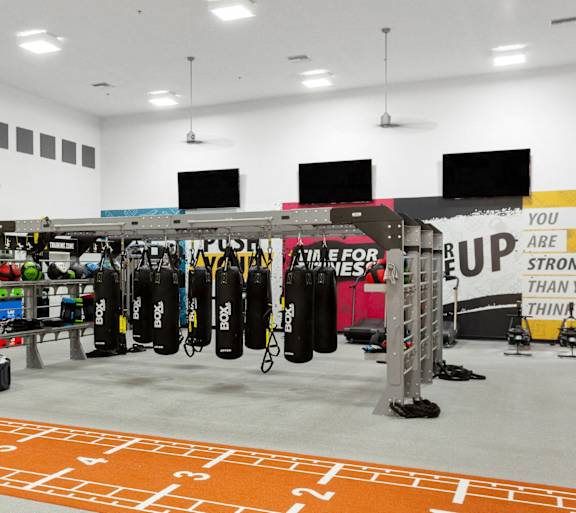 A gym with a variety of equipment including punching bags and weightlifting equipment.