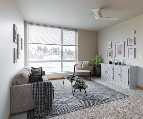 A living room with a grey couch, a chair, a table, and a rug.