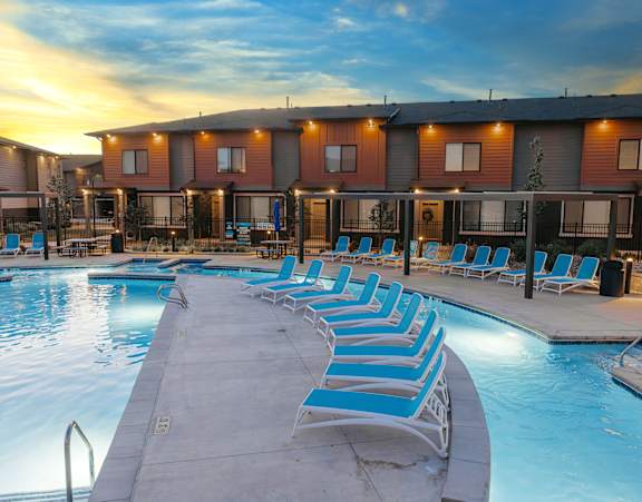 Woman wearing straw hat and white shirt is sitting in hammock at H2O Townhomes, West Valley City, UT