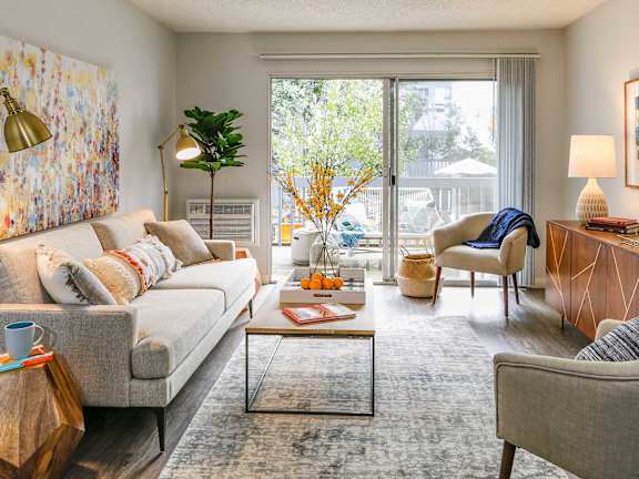 A living room with a grey sofa, a coffee table, a side table, and a painting on the wall.