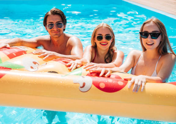three people in a swimming pool with an inflatable raft