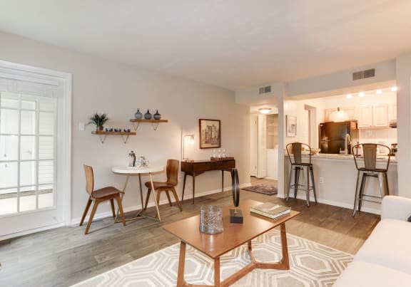 a living room with a couch a table and chairs and a kitchen in the background at Madison at Eden Brook, Columbia, 21046