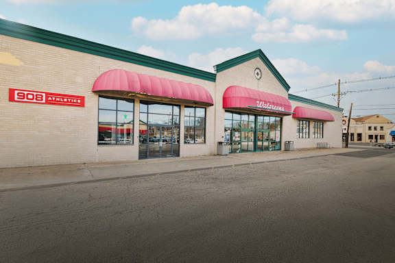 the exterior of a gas station with two buildings with red awnings