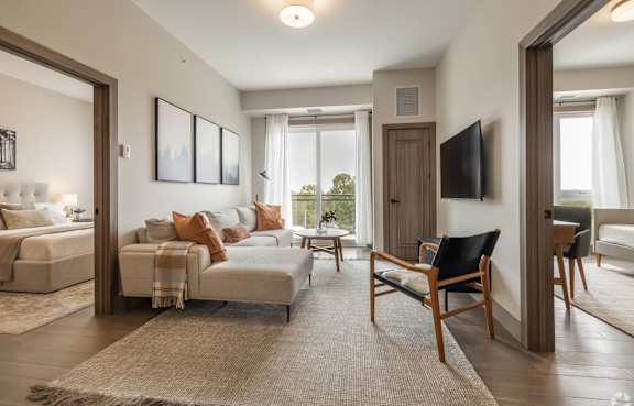 A living room with a white couch and a wooden chair.