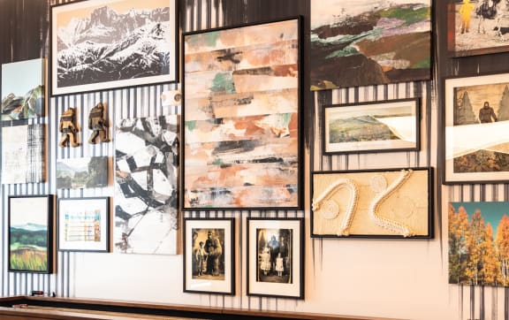 a wall of pictures on display in a gallery with a bench