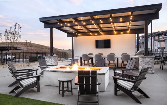 a patio with a fire pit and chairs and a tv