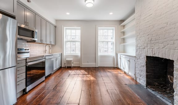 a kitchen with a large brick fireplace and hardwood floors
