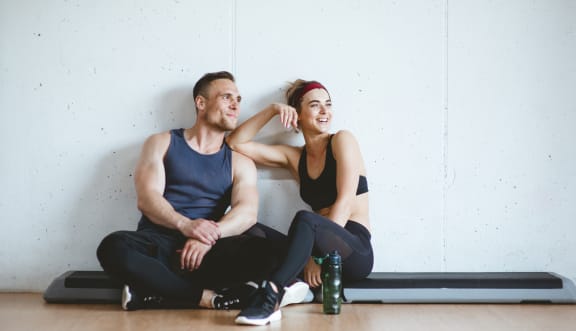 a man and a woman sitting on the floor at a gym