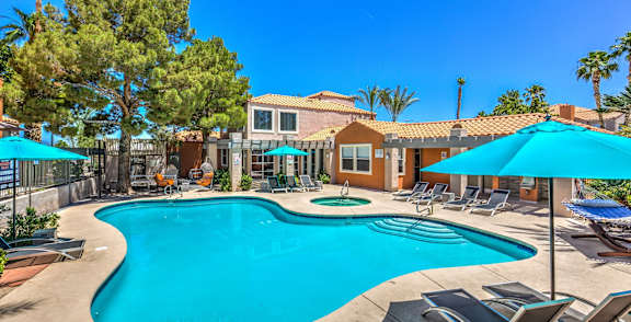 A swimming pool surrounded by lounge chairs and umbrellas.