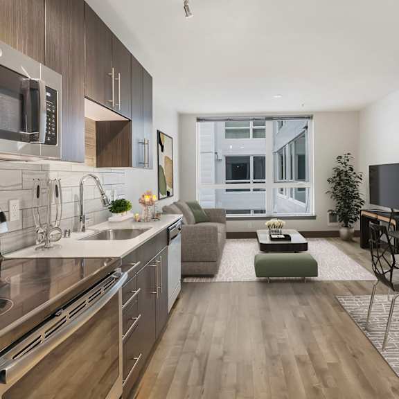 A modern kitchen with stainless steel appliances and wooden flooring.