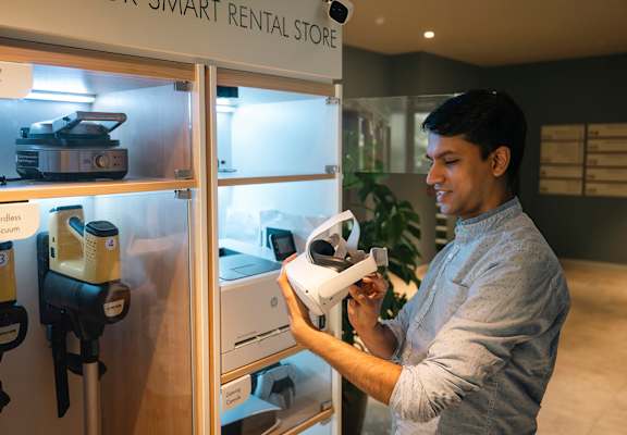 A man is holding a white drone in a smart rental store.