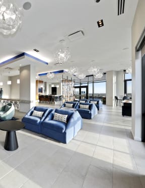 a lobby with blue couches and chairs and a large chandelier hanging from the ceiling at Aurora apartment in North Bethesda, Maryland