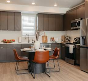 A modern kitchen with a wooden table and white chairs.