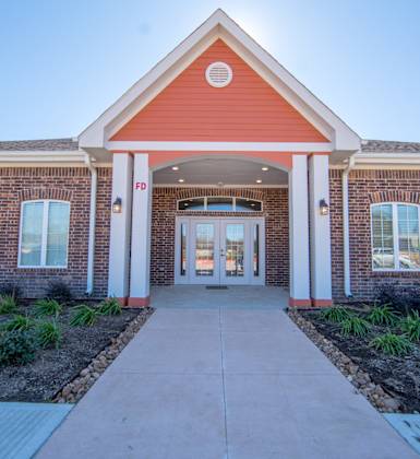 a brick building with a red roof and white pillars