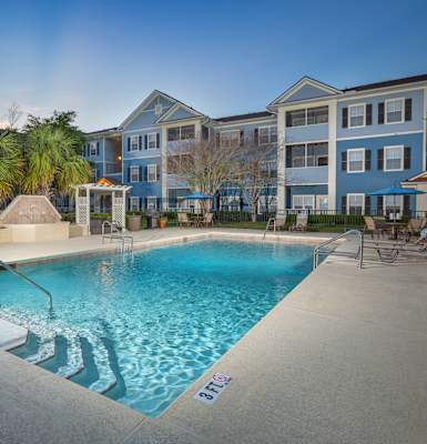 A swimming pool surrounded by a concrete floor and a white fence. at Magnolia Village Apartments, Jacksonville, FL, 32207