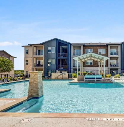 A large swimming pool in front of a modern apartment building.