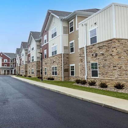 A parking lot in front of a row of apartment buildings.