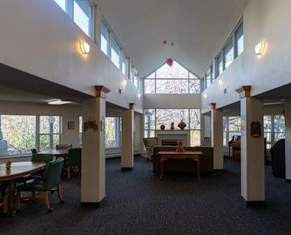 a view of the lobby of a library with tables and chairs and large windows