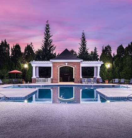 a swimming pool with a brick pool house and a pink sky