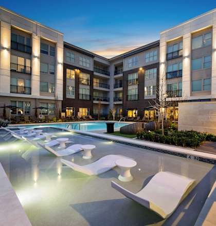 a swimming pool with lounge chairs in front of an apartment building