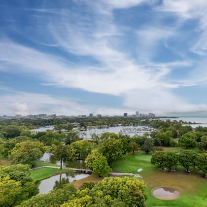 A beautiful aerial view of a park with a lake and a city skyline in the distance.