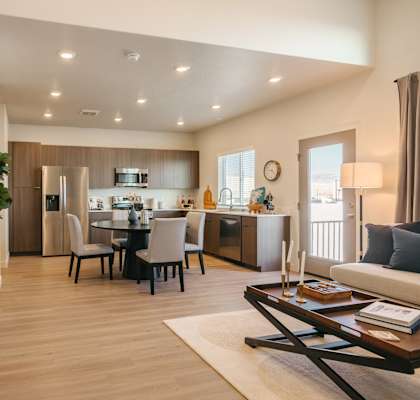A modern living room with a dining area and a kitchen in the background.