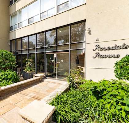 an office building with a walkway and plants in front of it
