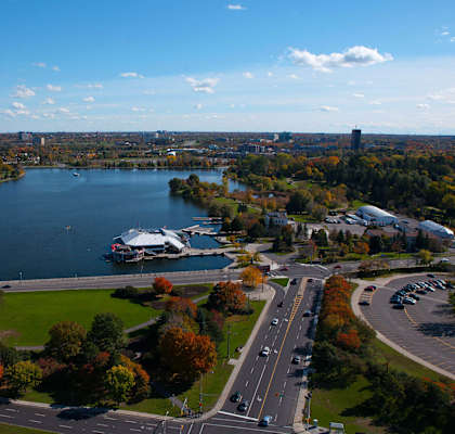 A lake surrounded by trees and a road with cars on it.