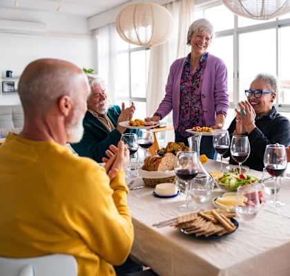 A group of people are gathered around a table, enjoying a meal and each other's company.