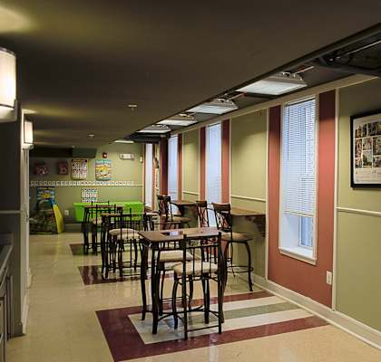 a dining area with tables and chairs in a room with windows