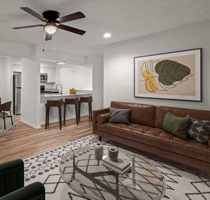 A living room with a brown couch, a dining table with chairs, and a ceiling fan.