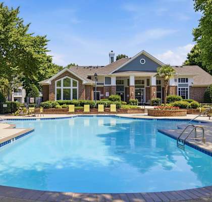 A large swimming pool in front of a building with a poolside lounge.