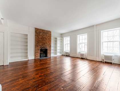 an empty living room with hardwood floors and a brick fireplace