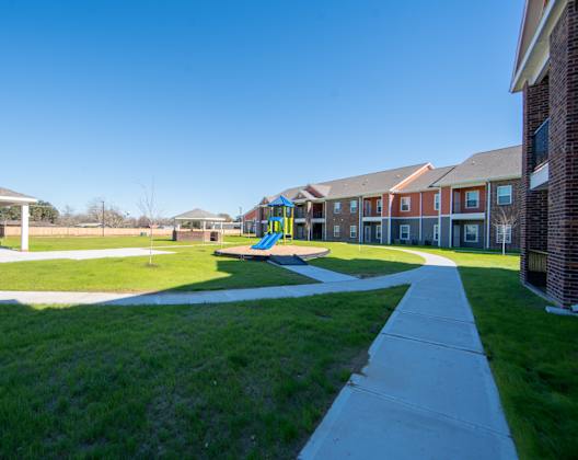 a playground with a slide in the middle of a grassy area